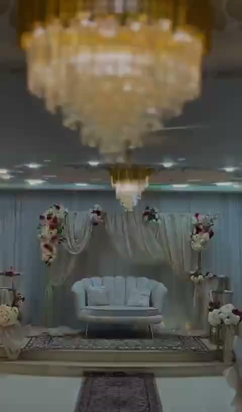 Estrade des mariés : banquette blanche capitonnée, tenture drapée et compositions florales