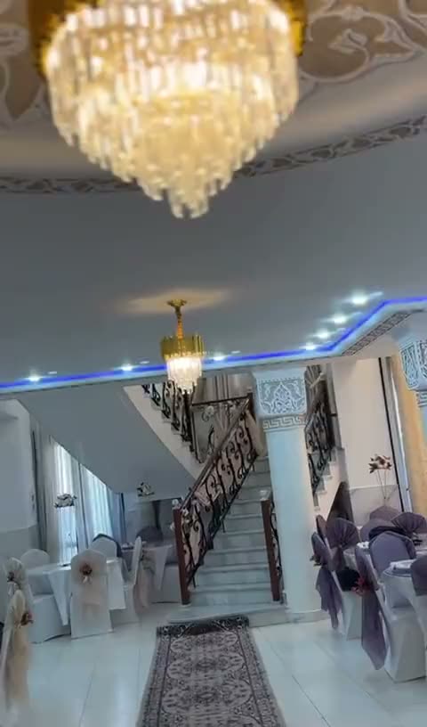 Hall d'entrée avec grand escalier, rampe en fer forgé et lustres en cristal