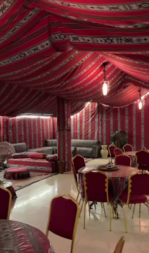 La khaïma montée à l'intérieur : tissus rayés rouges, banquettes basses et tapis traditionnels