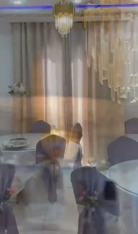 Salle en configuration lilas : housses blanches et nœuds mauves, lustre en cristal